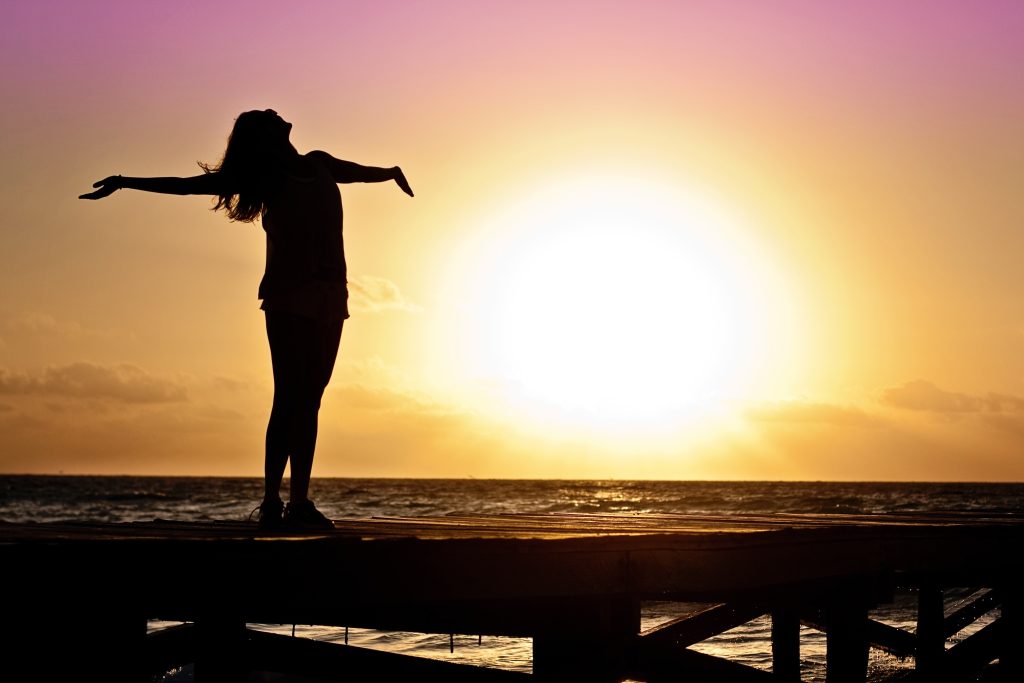 happy girl at sunset spreading her arms out