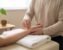 Practitioner taking a patient’s radial pulse at the wrist on a treatment table in a softly lit, neutral clinic setting.